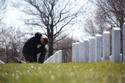 student knelling at veteran cemetary